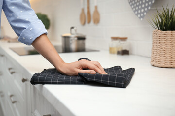 Wall Mural - Woman wiping white table with kitchen towel, closeup