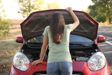 Wall Mural - Young woman near broken car outdoors, back view