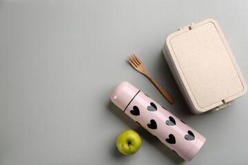 Poster - Thermos, lunch box with cutlery and apple on light grey background, flat lay. Space for text