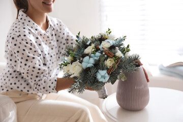 Wall Mural - Woman putting beautiful wedding winter bouquet in vase at home, closeup