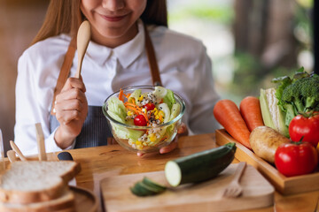 Wall Mural - Closeup image of a female chef cooking fresh mixed vegetables salad in kitchen