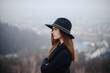 © WellStock - Side view of woman in hat standing at dark autumn park