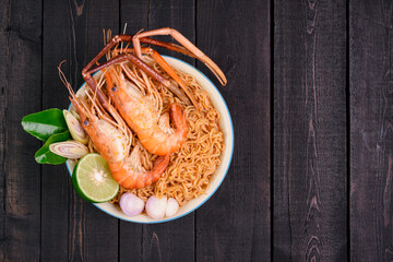 Wall Mural - Ramen Instant Noodles in Spicy Shrimp Soup Tom Yum Kung - Asian style food. Placed on a black table with copy space, top view.