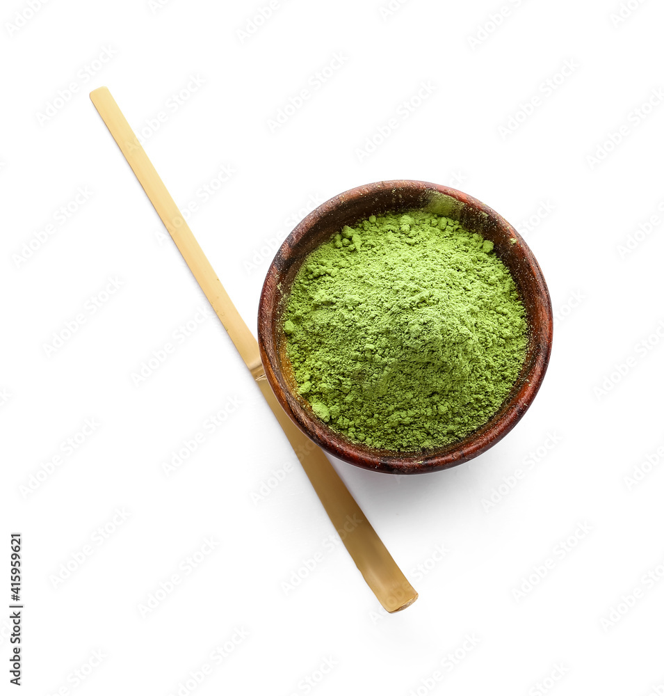Bowl with powdered matcha tea and chashaku on white background