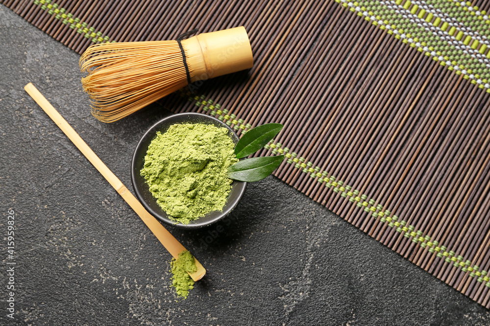 Bowl with powdered matcha tea, chasen and chashaku on dark background