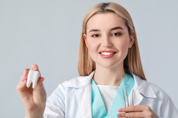 Wall Mural - Female dentist on light background