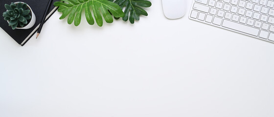 Horizontal photo of minimal office desk with notebook, wireless keyboard and copy space on white background.