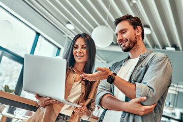 Wall Mural - Low angle view of female and male employees looking at laptop screen.