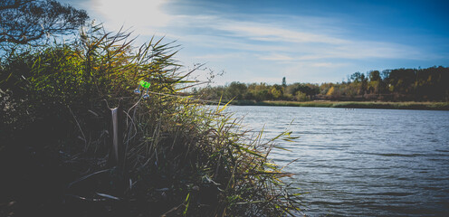 Fishing bottom tackle with green bell on the lake shore in autumn.