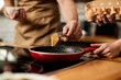 © Drazen - Close-up of couple using butter while preparing meal in the kitchen.