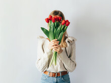 Portrait Of A Stylish Young Woman Hiding Her Face With A Bouquet Of Red Tulips.