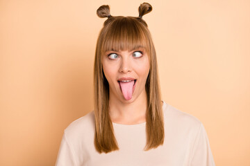 Wall Mural - Photo portrait of childish crazy girl showing tongue grimacing wearing t-shirt isolated on pastel beige color background