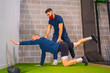 © unai - Personal trainer in the gym correcting stretching in the coronavirus pandemic, a new normal. With protective face mask