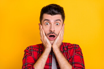 Sticker - Photo of shocked funky young guy wear checkered shirt arms cheeks open mouth isolated yellow color background