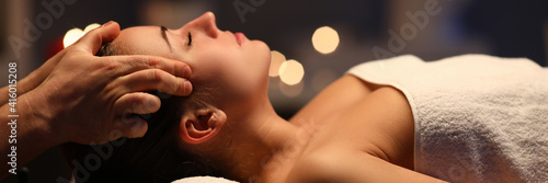 Woman lay on couch on her back with closed eyes and enjoy. Man make relaxing and therapeutic head massage at weight. Spa client has thrown her head back and rejuvenate. Wellness procedures in spa © H_Ko