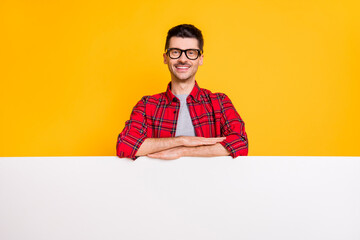 Photo of charming cheerful man wear glasses stand behind white card isolated on yellow color background