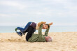 © Victor - Funny boy and his grandfather playing stretched out in the sand on the beach