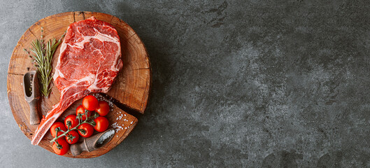 Wall Mural - fresh raw cowboy tomahawk steak on a round wooden cutting board for meat