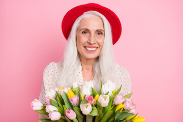 Poster - Portrait of attractive cheerful grey-haired granny holding tulips romance event floristry shop isolated over pink pastel color background