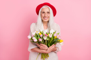 Poster - Portrait of attractive cheerful grey-haired granny holding in hands tulips romance floristry isolated over pink pastel color background