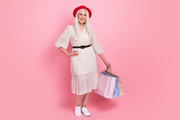 Poster - Full length body size view of attractive cheerful grey-haired woman posing carrying new things isolated over pink pastel color background