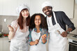 © sofiko14 - Young joyful multiethnic family, with faces stained with flour, having fun baking pie or cookies at the kitchen. Parenthood and childhood concept