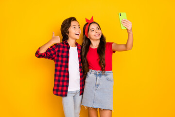 Sticker - Photo of two kids take selfie girl hold phone boy raise thumb up wear red casual clothes isolated yellow color background