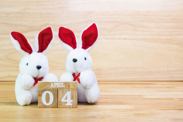 White rabbit doll with wood text April 4 on wood table copy space 