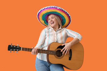 Wall Mural - Mature Mexican woman in sombrero hat and with guitar on color background