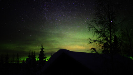Wall Mural - northern lights in clouds over a hut in swedish lapland