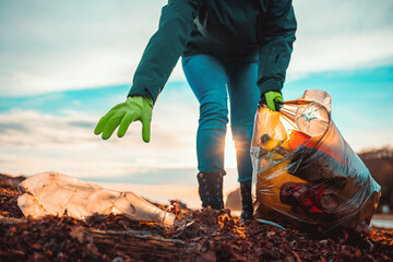 Wall Mural - A volunteer collects garbage on a muddy beach. Close-up. The concept of Earth Day. Bottom view