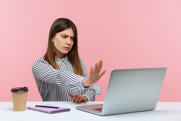 Wall Mural - Serious concerned woman office worker showing stop gesture to laptop screen, warning with prohibition sign talking on video call, online communication. Indoor studio shot isolated on pink background