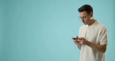 Wall Mural - young man with mobile phone playing game on color background