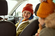 © pressmaster - Happy young mother in warm winterwear looking at her little daughter on backseat