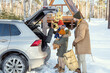 © pressmaster - Contemporary family of three in winterwear putting their buggage into car trunk
