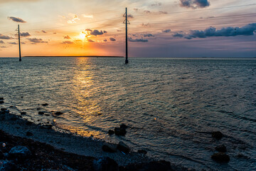 Wall Mural - Sunset in Islamorada, Florida Keys with sky power lines pylons and water on gulf of Mexico or Atlantic Ocean horizon island rocks with view on coast shore