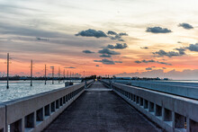 Cloudy Sky At Sunrise In Islamorada, Florida Keys With Colorful Sky By Overseas Highway Road Of Gulf Of Mexico With Power Lines And Pedestrian Bridge, People Fishing