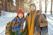 © pressmaster - Young smiling couple in winterwear standing in front of camera in the forest