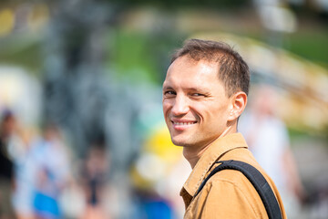 Closeup portrait of young man happy tourist person people smiling with bokeh background of city park in Ukraine