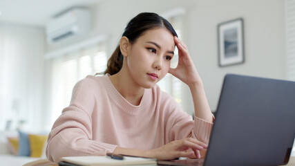 Back rear view young asian woman employee work from home using computer notebook videocall meeting conference angry annoy with low poor unreliable internet wifi connection problem issue outage.