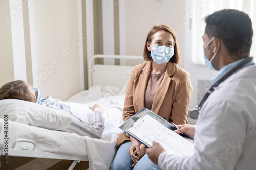 Young female in protective mask consulting with doctor about her sick friend © pressmaster