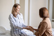 © pressmaster - Young female patient sitting on bed in front of her friend during conversation
