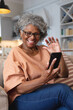 © Wavebreak Media - African american senior woman smiling and waving while having a video call on smartphone at home