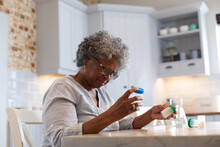 Thoughtful African American Senior Woman Holding Empty Medication Containers At Home