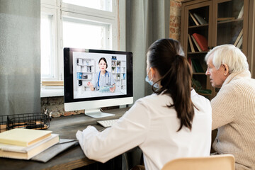 Sticker - Sick senior man and young general practitioner sitting in front of computer