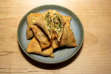 A delicious pile of vegetable Indian samosas on a wooden kitchen table