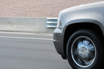 The front end of a silver, fast-moving vehicle circulating on a U.S. freeway, conveying the concepts of speed and travel