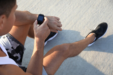 Poster - Man checking fitness tracker after training outdoors, closeup