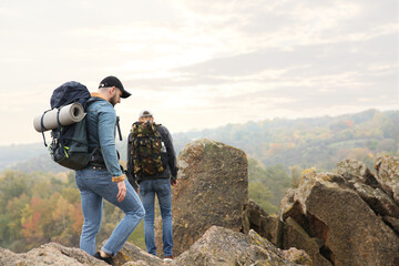 Poster - Hikers with backpacks climbing up mountain on autumn day