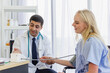 © nationkp - male doctor examines the symptoms of a woman is patient at working desk and talks about his illness